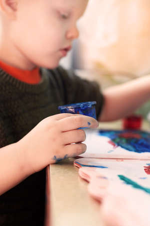 A three-year-old boy paints with gouache coloring, leisure and child development.の写真素材