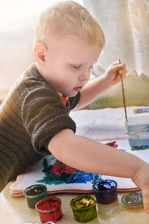 A three-year-old boy paints with gouache coloring, leisure and child development.の写真素材