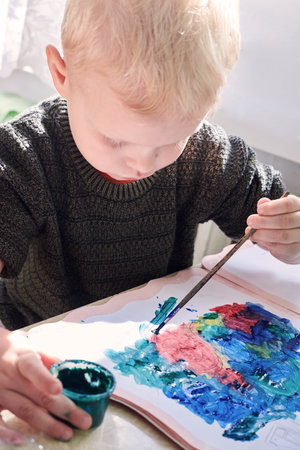 A three-year-old boy paints with gouache coloring, leisure and child development.の写真素材