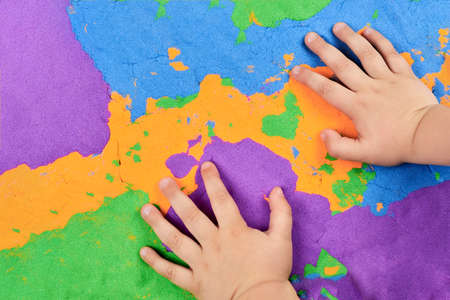 Little boy's hands on bright kinetic sand, children's entertainment.の写真素材