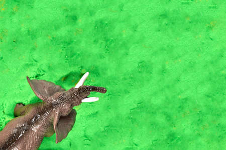 Toy elephant on green kinetic sand, children's games and entertainment, copy space.