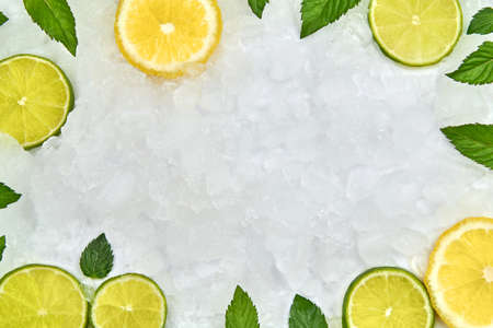 Pieces of lime, lemon and mint leaves on ice, border, copy space.の写真素材