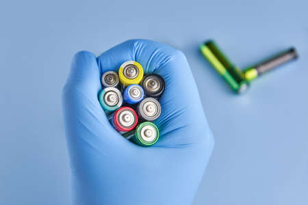 Batteries in the hand of a man in a protective glove, battery recycling theme.
