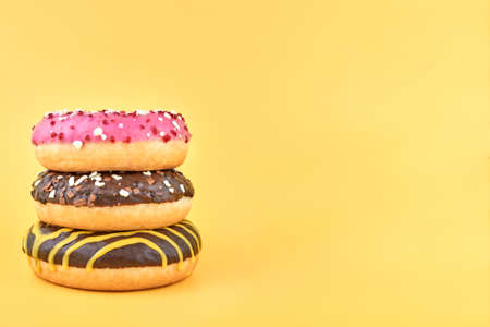 Three bright donuts on a yellow background, copy space.の写真素材