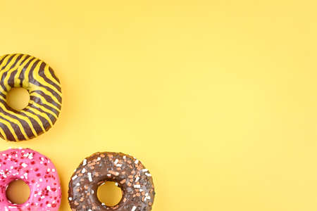 Three bright donuts on a yellow background, copy space.の写真素材