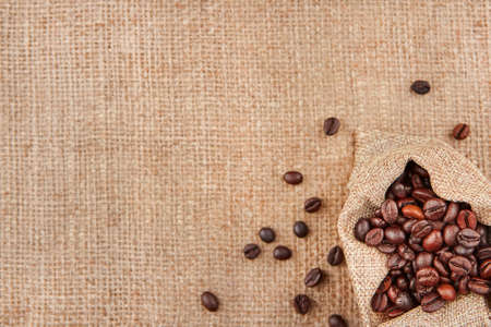 Coffee beans in a bag on a background of burlap, top view, copy space.の写真素材