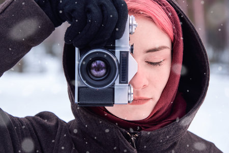 Portrait of woman with bright pink hair with retro camera in winter forest.の写真素材