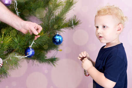 Grandfather and his little grandson decorate the Christmas tree.