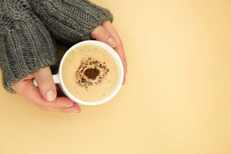 A woman's hands in a warm sweater are holding a cup of coffee, copy space.の写真素材