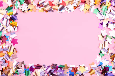 Bright colorful star-shaped confetti sparkles on a pink background, copy space, the theme of a holiday and a birthday.の写真素材