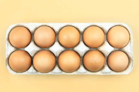 Eggs in a paper tray on a beige background, top view.