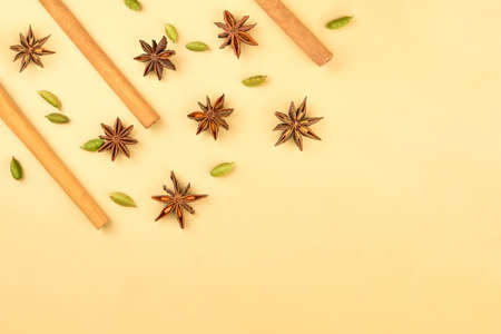 Cinnamon sticks, cardamom and star anise on a beige background, top view, copy space.