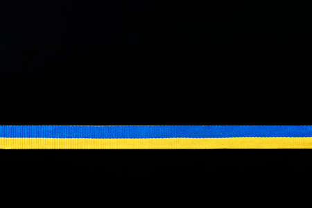 Ribbon in the color of the Ukrainian flag on a black background, copy space.の写真素材