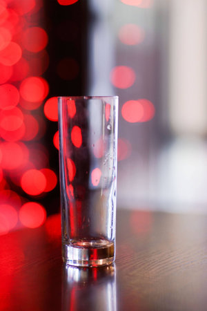 Empty glass with water drops in the coffee shop amid the red lightsの写真素材
