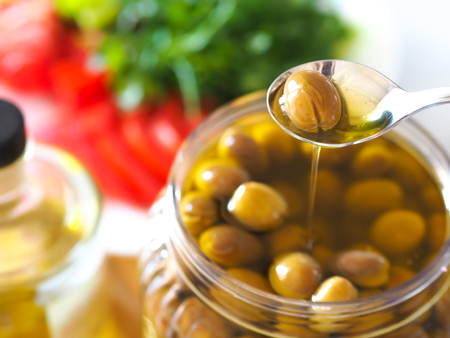 homemade green olives. close-up of organic olives and olive oil in jarの写真素材