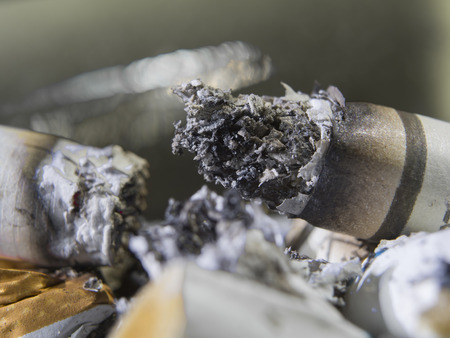 close-up smoking cigarette and cigarette butts in ashtrayの写真素材