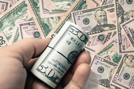 50 american dollar created background texture and person holding roll coin in handの写真素材