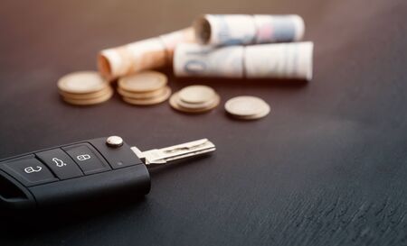 car key and coins on black background, concept photo for car finance industryの写真素材