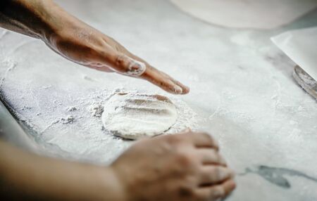 woman kneading dough with her hand on the kitchen counter
