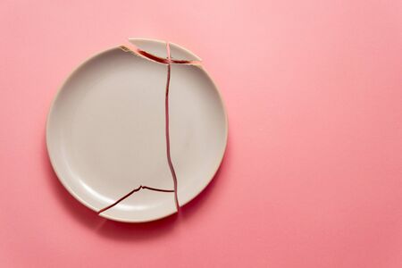 broken white plate on pink background, concept visual