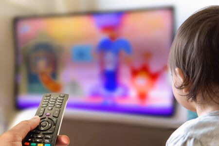 little boy watching television and television remote control