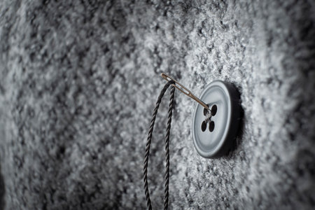 button on thick coat fabric and thread with needle on it