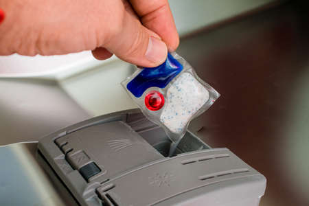 man puts tablet detergent in dishwasher detergent section