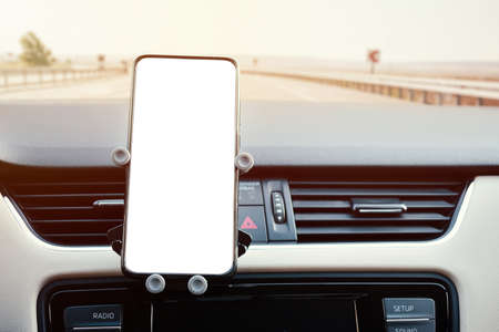 phone holder attached to the ventilation grille in the vehicle and a phone with a white screen on itの写真素材