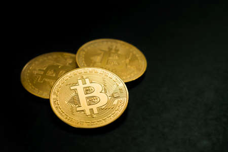 three close-up bitcoin coins on black backgroundの写真素材