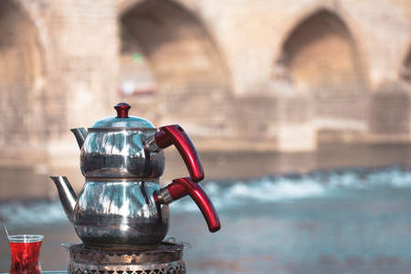 Turkish black tea and teapot in Diyarbakir historical bridge viewの写真素材