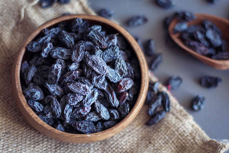 black raisins in wooden bowl with black backgroundの写真素材