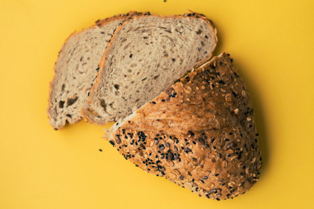 Sliced whole wheat bread on yellow background with sesame seeds