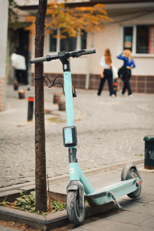 electric scooter tied to a tree on the sidewalk on the streetの写真素材