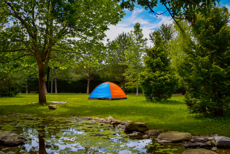 camping tent set up by the lake in the park forestの写真素材