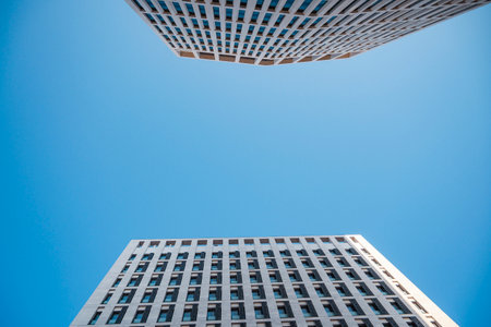 A visual of two skyscrapers standing side by side, looking up into the sky from below with blu skyの写真素材