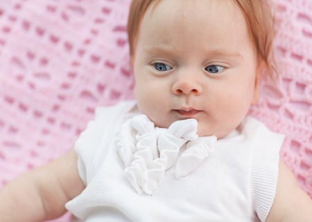 The baby lies on a pink towel. She's in pink shorts and a white blouse.の写真素材