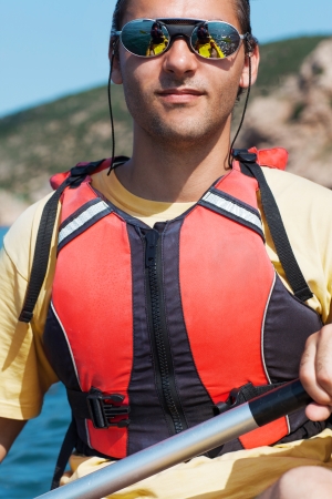 Young muscular sportsman kayaking in the sunshineの写真素材