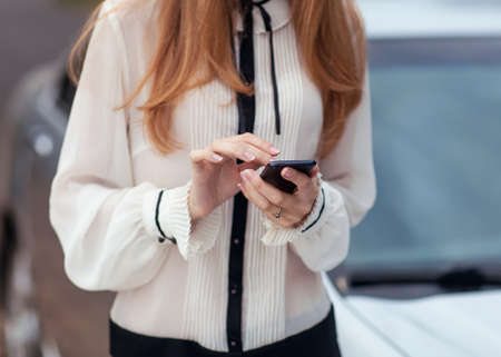 Young beautiful woman writes an SMS to your mobile phone の写真素材