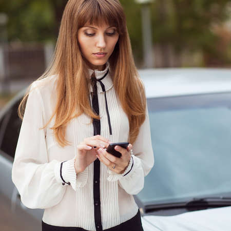 Young beautiful woman writes an SMS to your mobile phone の写真素材