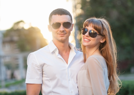 Young couple in love outdoor  They re wearing sunglasses  In the background, the rays of the setting sun の写真素材