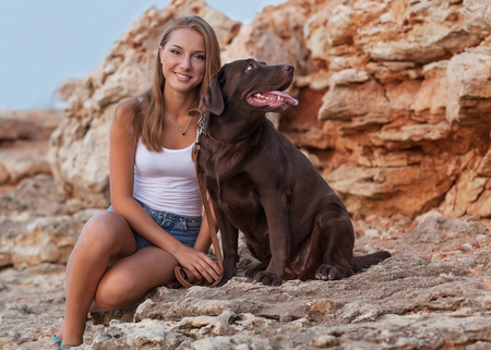 Portrait of a woman with her beautiful dog sitting outdoors の写真素材