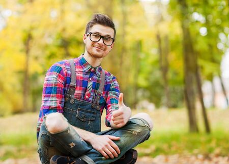 hipster guy sitting in the autumn park smilingの写真素材