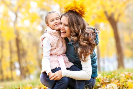 mother and daughter playing in autumn parkの写真素材