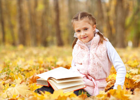 girl in autumn park reading a bookの写真素材