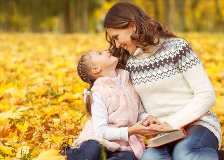 Mom and daughter having fun in autumn park.の写真素材
