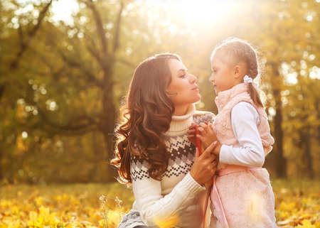 Mom and daughter having fun in autumn park.の写真素材