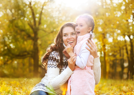 mother and daughter playing in autumn parkの写真素材