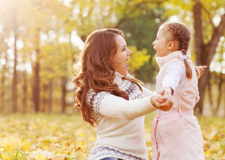 Mom and daughter having fun in autumn park の写真素材