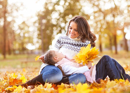 Little girl and her mother in the autumn parkの写真素材