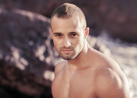 Portrait of a handsome young muscular man in swimtrunks with water ocean backgroundの写真素材